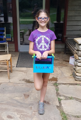 student showing off tool box she built in a middle school wood shop
