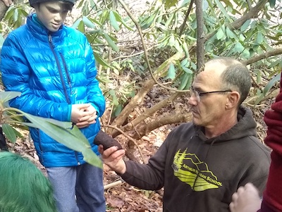 teacher showing a middle schooler an artifact from a archaeological dig
